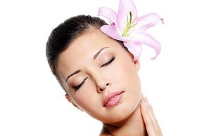 woman with pink Lily flower on ear closing her eyes